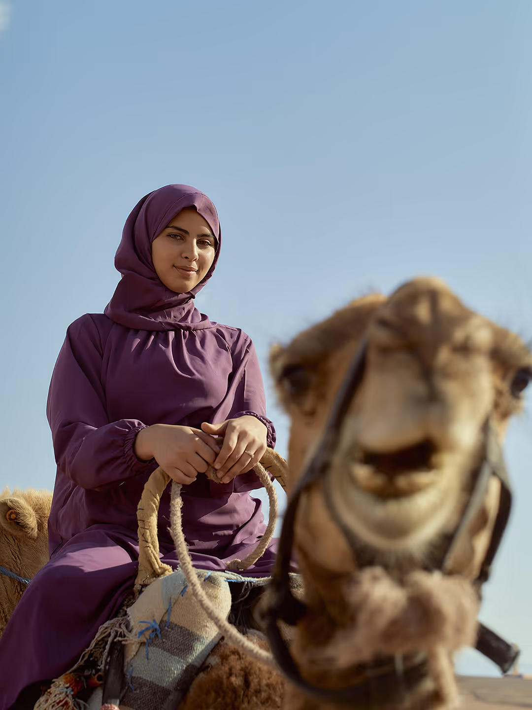 A smiling traveller riding a camel in the Moroccan Sahara